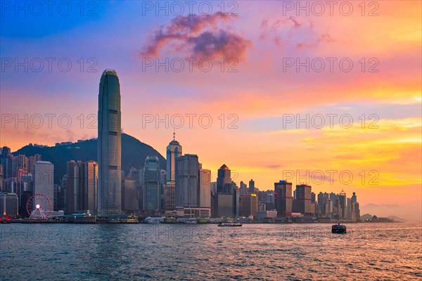 Hong Kong skyline cityscape downtown skyscrapers over Victoria Harbour in the evening with junk tourist ferry boat on sunset with dramatic sky. Hong Kong