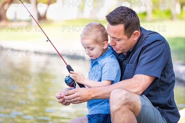 Young caucasian father and son having fun fishing at the lake