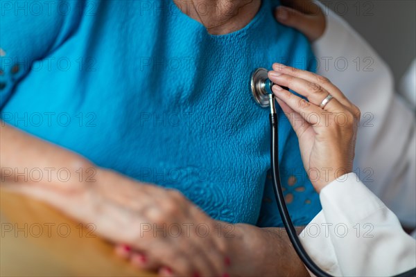 Female doctor checking the heart with stethoscope of senior adult woman