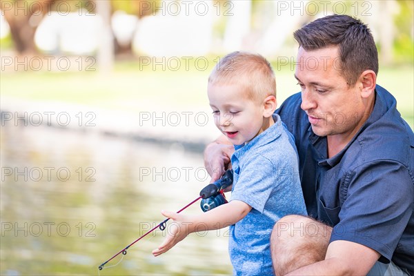 Young caucasian father and son having fun fishing at the lake