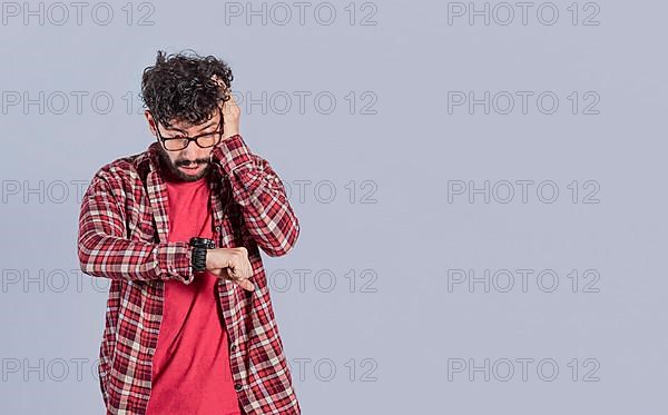 Worried handsome man looking at the time on the watch. Worried people looking at their watch