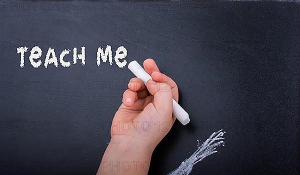 Hand holding white chalk and black board