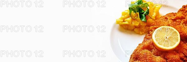 Delicious golden-brown fried Wiener Schnitzel with potato salad and a slice of lemon on a white plate,