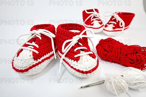 Baby shoes or crochet shoes in red and white isolated against a white background,