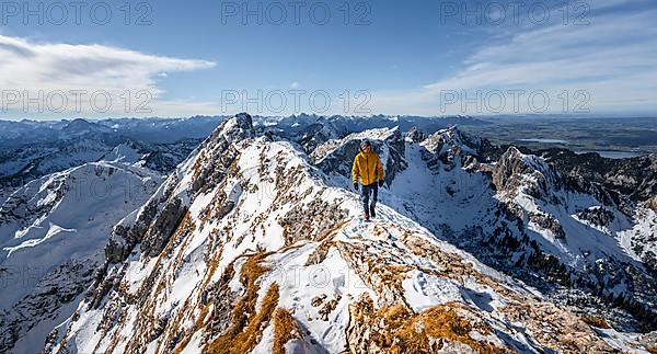 Climbers on a narrow rocky snowy ridge, behind peak crow