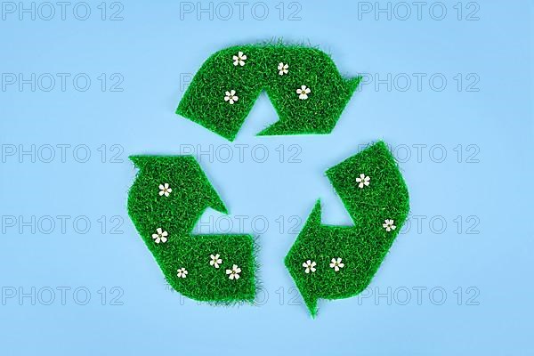 Recycling arrow symbol made from grass and flowers,