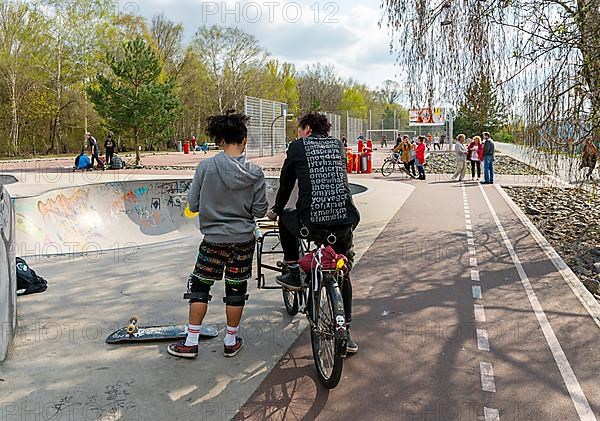 Skateboarders and cyclists at a skate pool in the Park am Gleisdreieck in Berlin-Mitte, Berlin