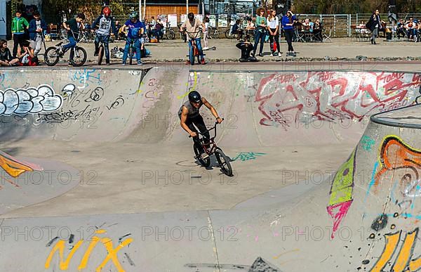 Skateboarders and cyclists at a skate pool in the Park am Gleisdreieck in Berlin-Mitte, Berlin