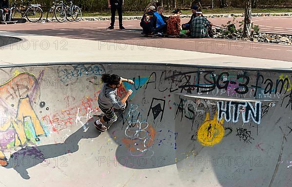 Skateboarders and cyclists at a skate pool in the Park am Gleisdreieck in Berlin-Mitte, Berlin