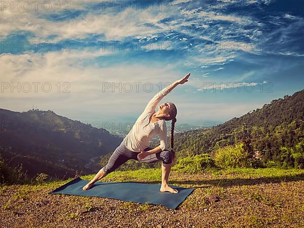 Vintage retro effect hipster style image of sporty fit woman practices yoga asana Utthita Parsvakonasana