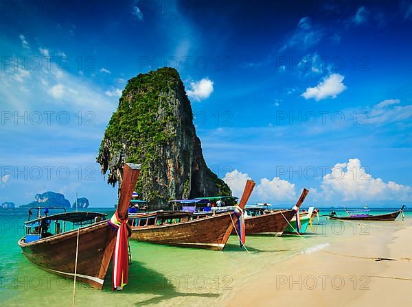 Long tail boat on tropical beach with limestone rock