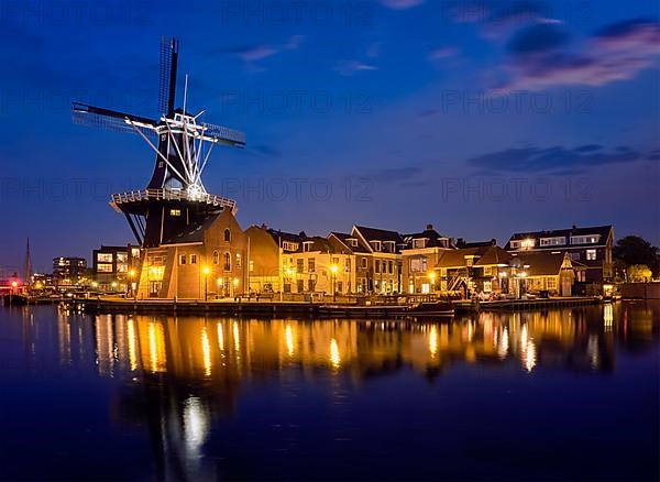 View of Harlem landmark windmill De Adriaan on Spaarne river in the night illuminated. Harlem