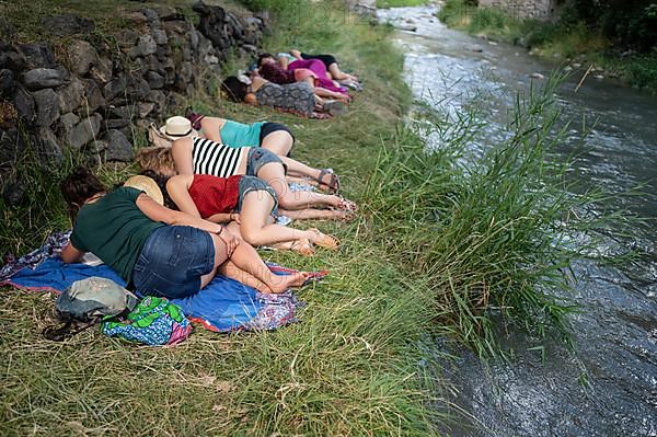 Group of people take a nap by the river at Pirineos Sur International Festival of Cultures in Sallent de Gallego