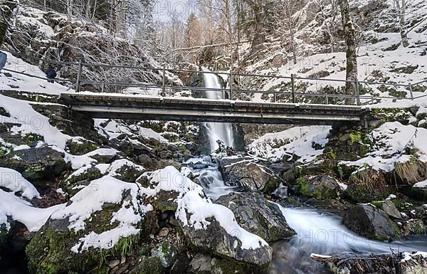 Bridge in front of waterfall in winter landscape