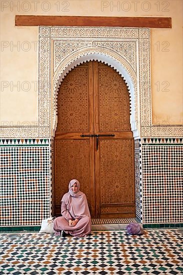 Moroccan woman in front of a traditional wooden gate