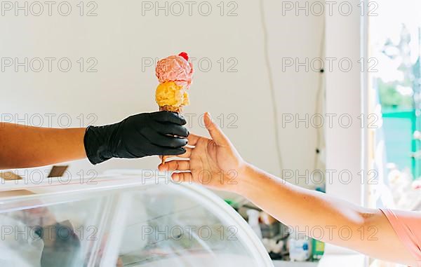 Close-up of hands buying an ice cream. Close up of hands receiving an ice cream cone. Close up of person buying an ice cream cone