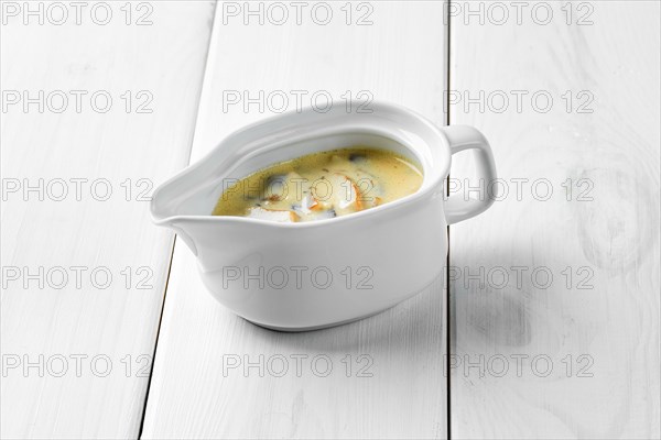 Mushroom sauce in ceramic gravy boat on white wooden table