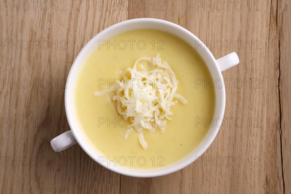 Top view of soup puree with cheese and mushrooms on wooden table