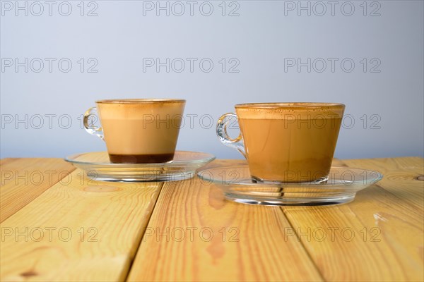 Cappuccino in transparent glass cup on wooden table