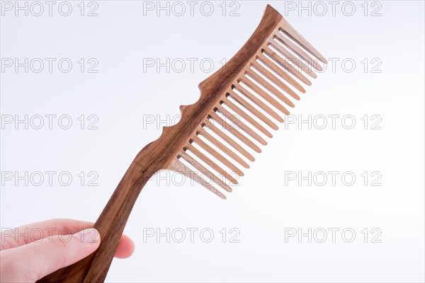 Hand holding a wooden hair comb on a white background