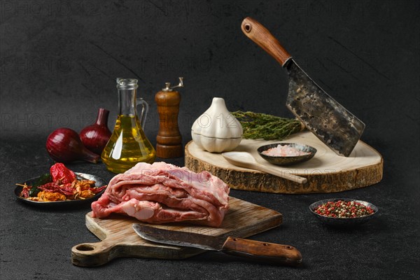 Raw veal ribs with ingredients for cooking on black background