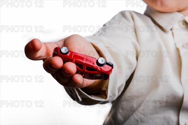 Baby hand holding a red car on a white background