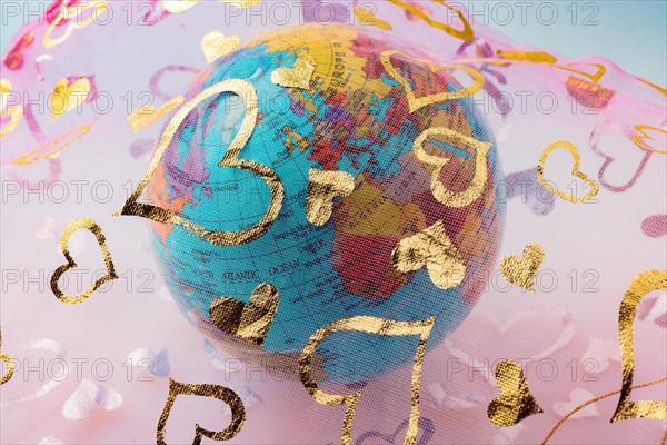 Little model globe under a fabric with heart patterns