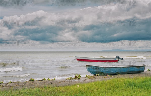 Two wooden fishing boats on the shore of a beautiful lake. Two fishing boats parked on the shore of a lake