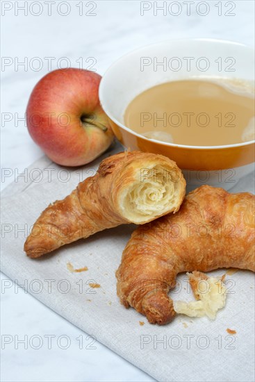 Coffee with milk in bowl and croissant