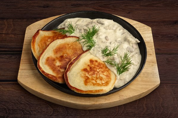 Flapjack with mushroom sauce on wooden plate. Top view