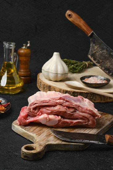 Raw veal ribs with ingredients for cooking on black background