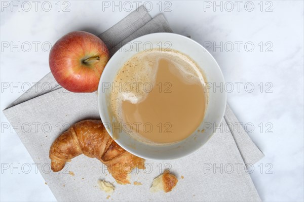 Coffee with milk in bowl and croissant