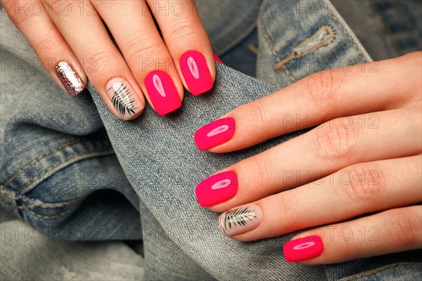 Bright neon manicure on female hands on the background of jeans. Nail design. Beauty hands