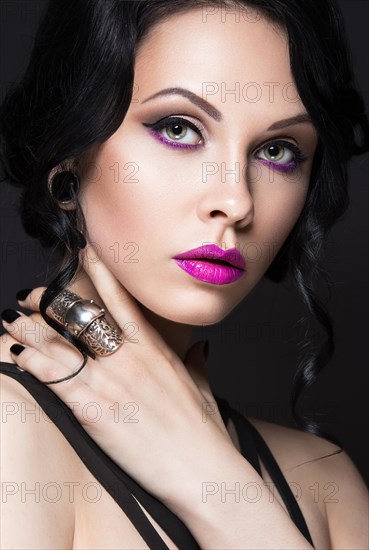 Beautiful Girl in the Gothic style with leather accessories and bright makeup. Beauty face. Picture taken in the studio on a black background