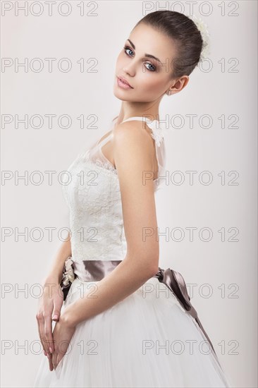 Portrait of a beautiful blond girl in image of the bride with purple flowers on her head. Beauty face. Photo shot in the Studio on a grey background