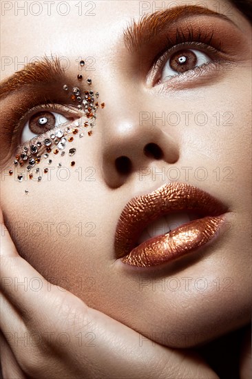 Beautiful girl with a gentle make-up and crystals on the face. Close-up portrait. Beauty face. Picture taken in the studio