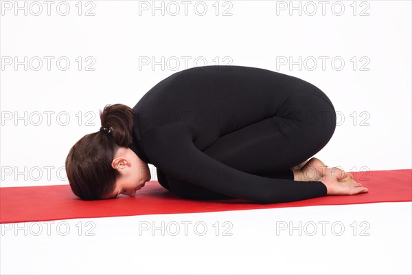Beautiful athletic girl in black suit doing yoga. Balasana asana child's pose. Isolated on white background