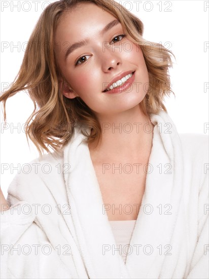 Beautiful tender young girl in a white coat with clean fresh skin posing in front of the camera. Beauty face. Skin care. Photo taken in studio on a white isolate background