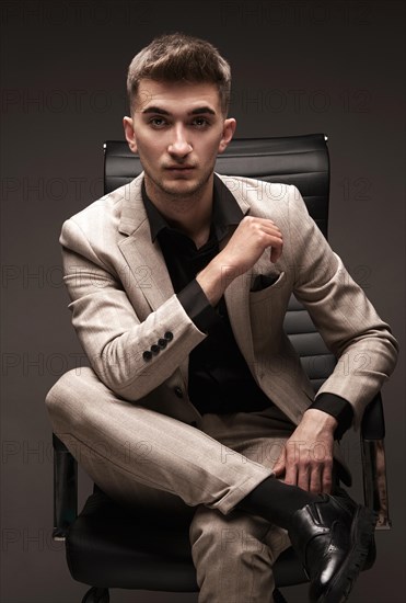 Handsome man in a classic suit in a leather chair. Photo taken in the studio
