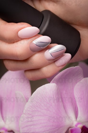 Purple neat manicure on female hands on a background of flowers. Nail design