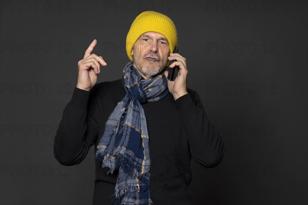 Elderly man with yellow winter cap excitedly talking on the phone