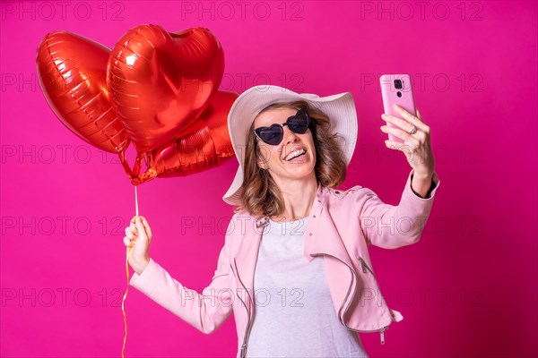 A caucasian woman having fun with a white hat in a nightclub with some heart balloons