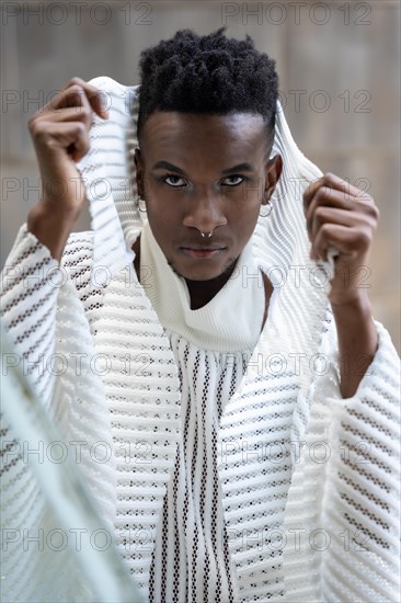 A young man of African ethnicity in a white contemporary suit and black leather boots