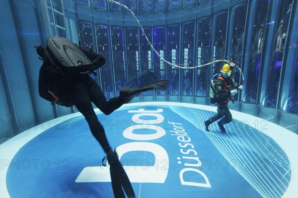 Divers swim in glass diving tower with logo