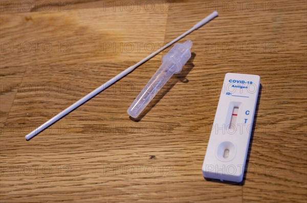 Close-up of a negative Corona rapid test cassette with collection swabs and test liquid on a wooden table