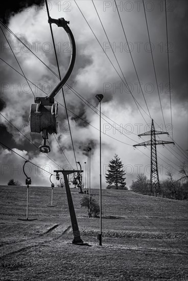 Ski lift at standstill due to lack of snow caused by climate change at the end of winter on a hill in Muensingen