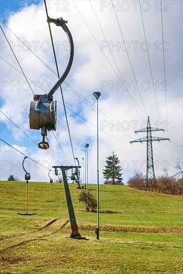 Ski lift at standstill due to lack of snow caused by climate change at the end of winter on a hill in Muensingen