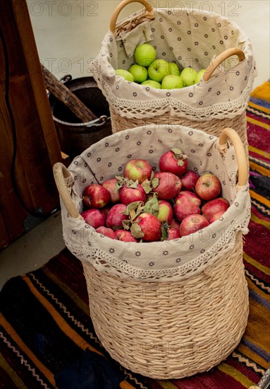 Red and green apples in straw baskets in display