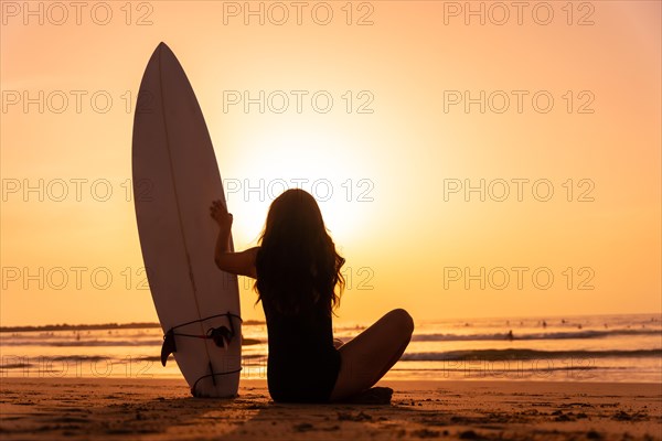 Silhouette surfer girl on the beach at sunset