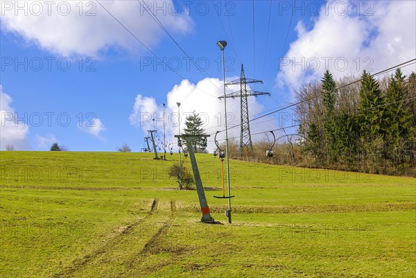 Ski lift at standstill due to lack of snow caused by climate change at the end of winter on a hill in Muensingen